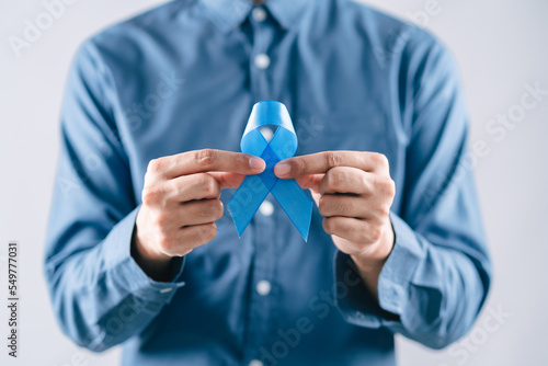 men hands holding Blue ribbon for supporting people living and illness, Colon cancer, Colorectal cancer, Child Abuse awareness, world diabetes day, International Men's Day