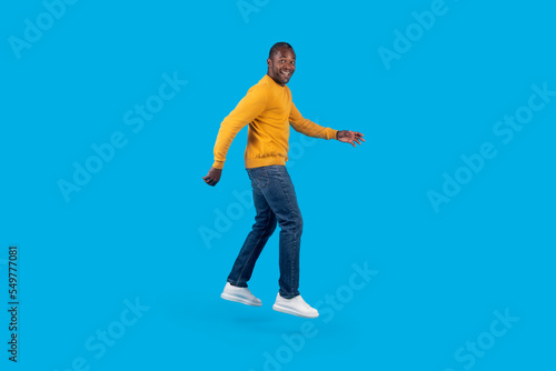 Emotional african american mature man jumping up on blue