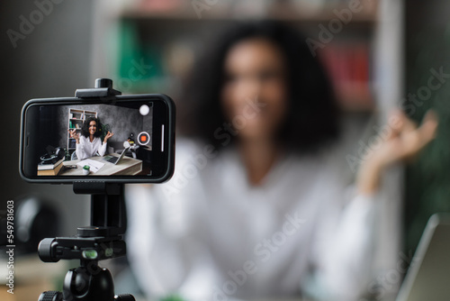 Slika na platnu Blurred relaxed young woman in casual wear sitting on workplace with modern laptop and meditating with closed eyes during recording video blog
