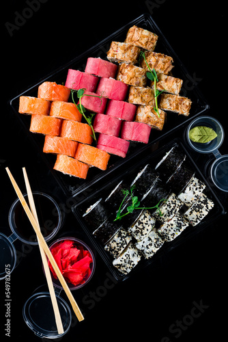 Sets of maki sushi rolls with tuna, salmon, cream cheese, rice paper, shrimp, sweet pepper, wasabi, ginger, soy sauce in box.