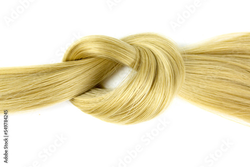 Blonde hair lock tied in knot. Lock of blonde wavy hair on white background, top view.