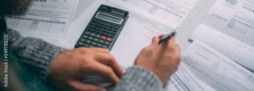 Close-up of a man's hands with a calculator and a lot of utility bills on the table. The man considers the costs of gas, electricity, heating. photo