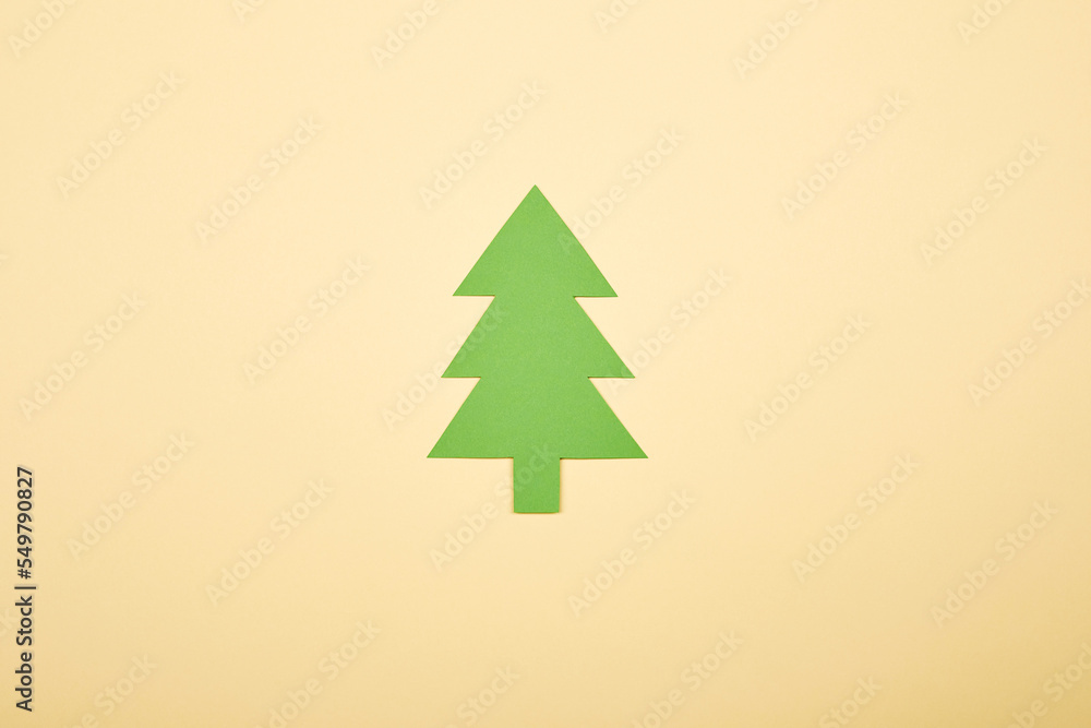 Obraz premium Green Сhristmas tree shape paper applique isolated on the bright solid fond plain yellow background. Postcard template