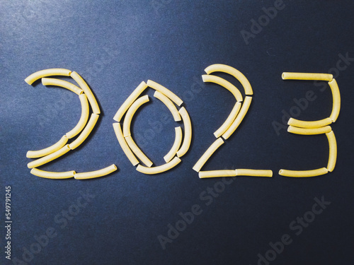 Année 2023 en pâtes macaronis sur papier noir, crise