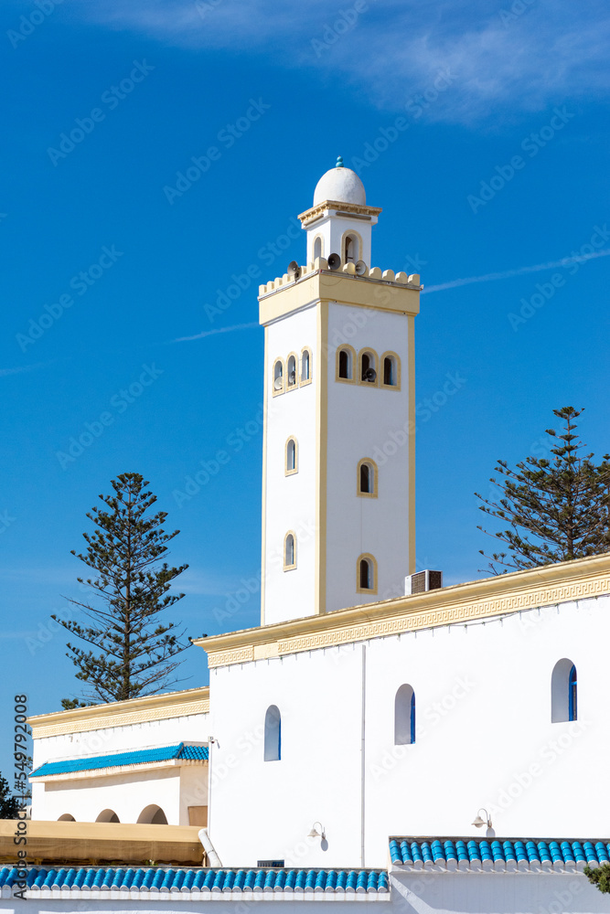 Low-angle view of the masjid's minaret against a blue sky.