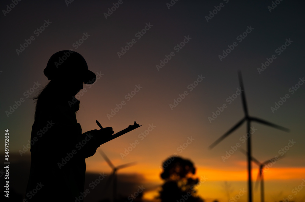 Asian Man engineers working and holding the report at wind turbine farm Power Generator Station on mountain,Thailand people,Technician man at site of work