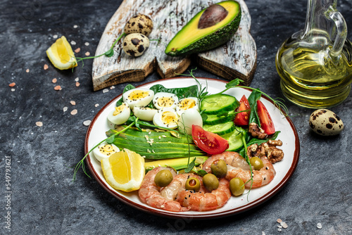 shrimps, prawns, soft fried egg, fresh salad, tomatoes, cucumbers and avocado on a dark background. Ketogenic diet breakfast. Keto, paleo lunch. Top view