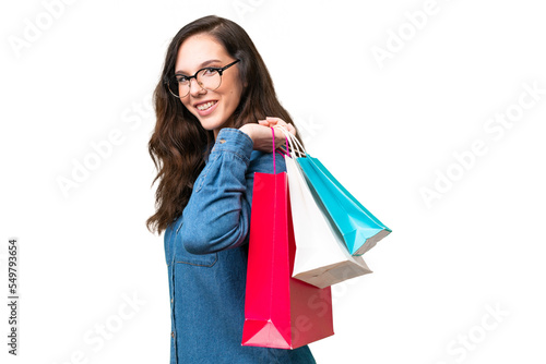 Young caucasian woman over isolated background holding shopping bags and smiling