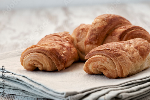 Delicious and fresh croissant on a light wooden background