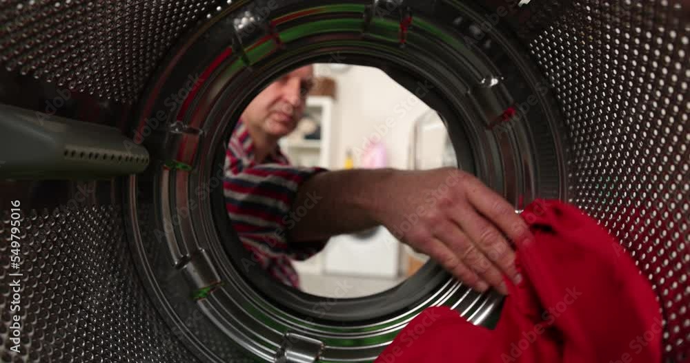 View from inside a washing machine, a man puts a colored wash into the washing machine View from inside a washing machine, a man puts a colored wash into the washing machine