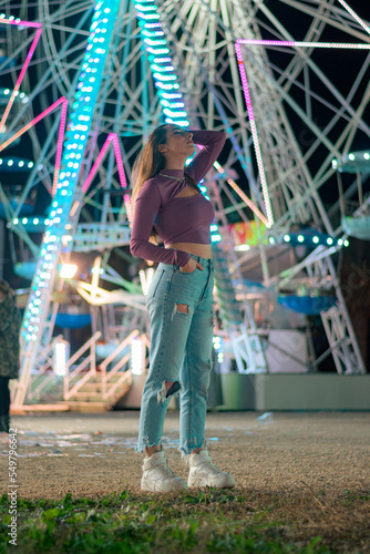 Young woman with the lights of a Ferris wheel in the background