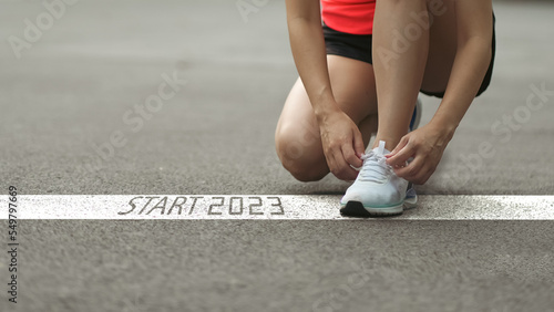 happy new year 2023,2023 symbolizes the start of the new year. Start with a woman preparing to run on the road engraved with the year 2023. The goal of Success. Getting ready for the new year