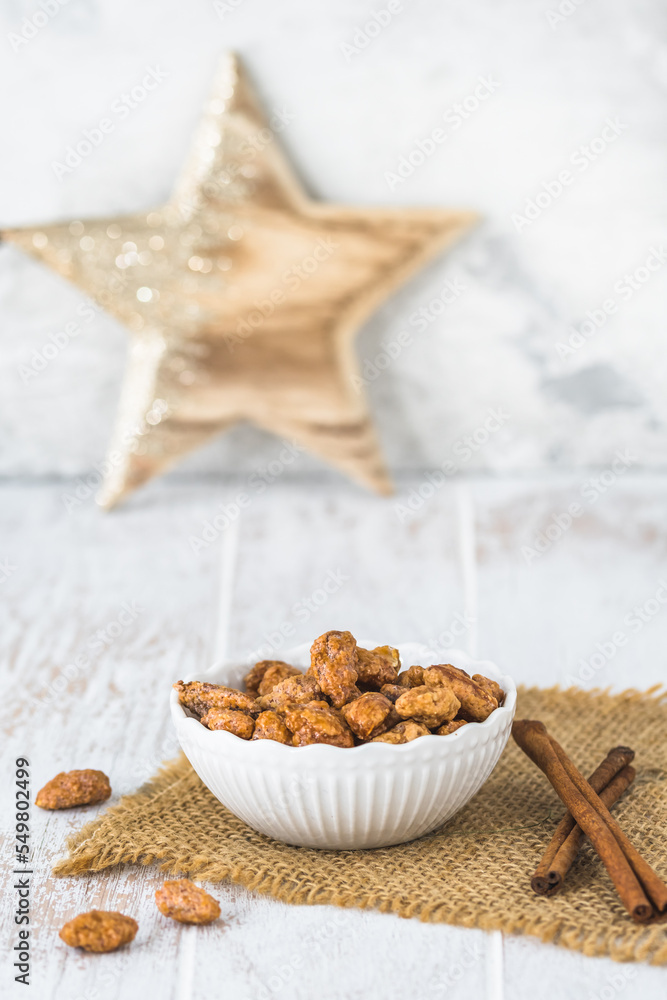 Bowl of sweet candied almonds on white rustic wooden background
