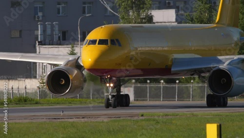 NOVOSIBIRSK, RUSSIAN FEDERATION - JUNY 12, 2022: Middle shot of cargo plane Tupolev of Aviastar-TU taxiing. Transport airline. Aircraft with yellow livery on the taxiway photo