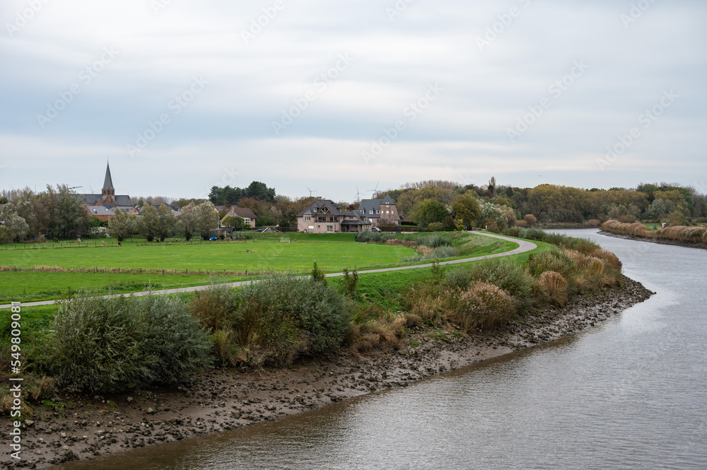 Berlare, East Flemish Region, Belgium, 11 02 2022 - View over the River Scheldt, vegetation and the village in the background