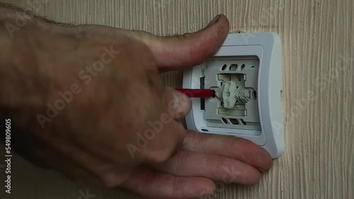 The electrician installs the circuit breaker with a screwdriver.