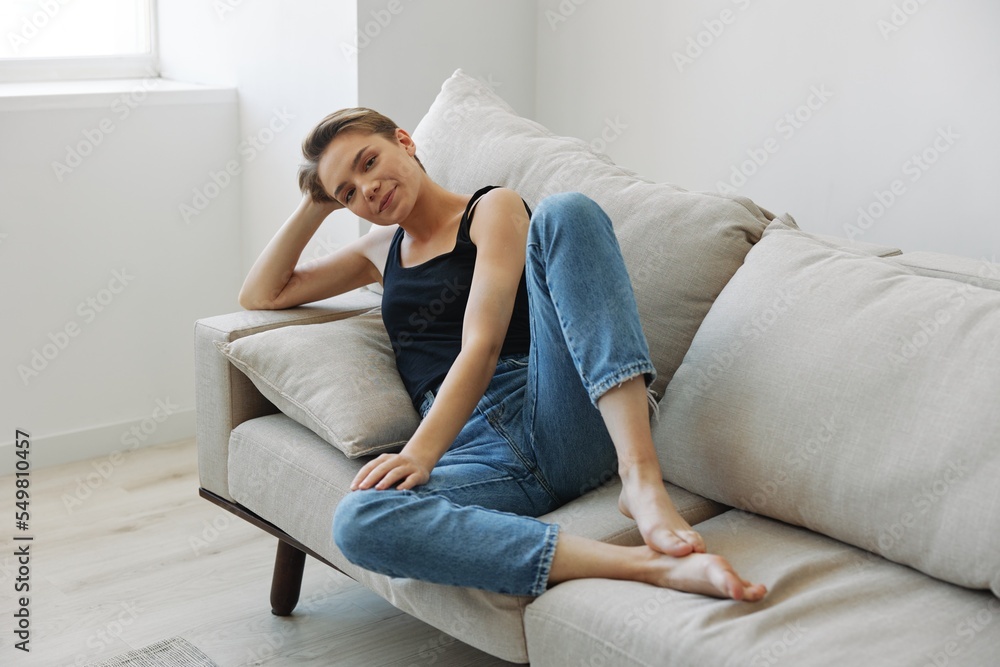 Young woman with short haircut hair having fun at home on the couch smile and happiness, vacation at home, natural posing without filters, free copy space