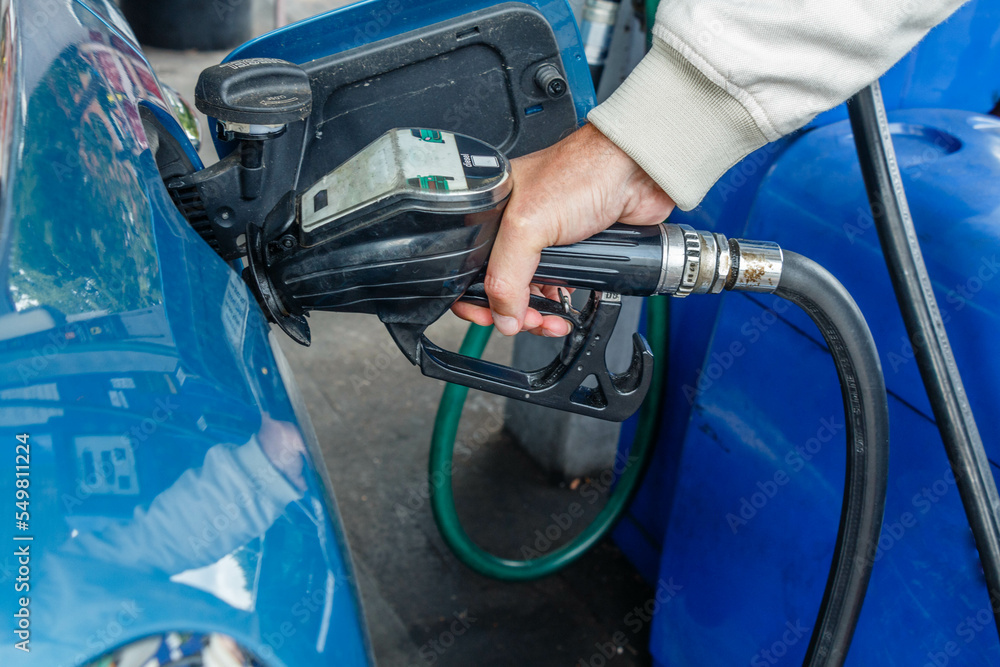 Close up of man hand refueling a blue car at a petrol station. Oil price crisis