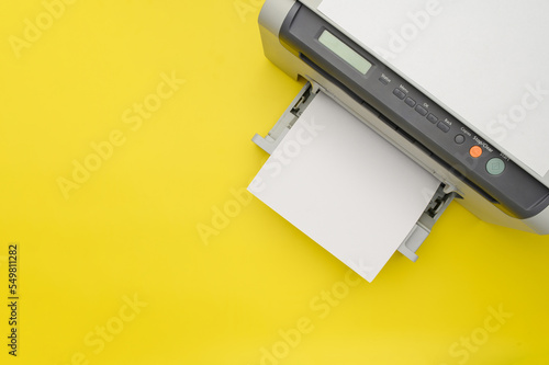Top view of the printer and a blank sheet of a4 paper on a yellow background