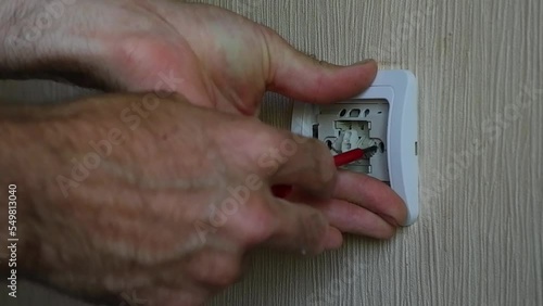 The electrician installs the circuit breaker with a screwdriver.