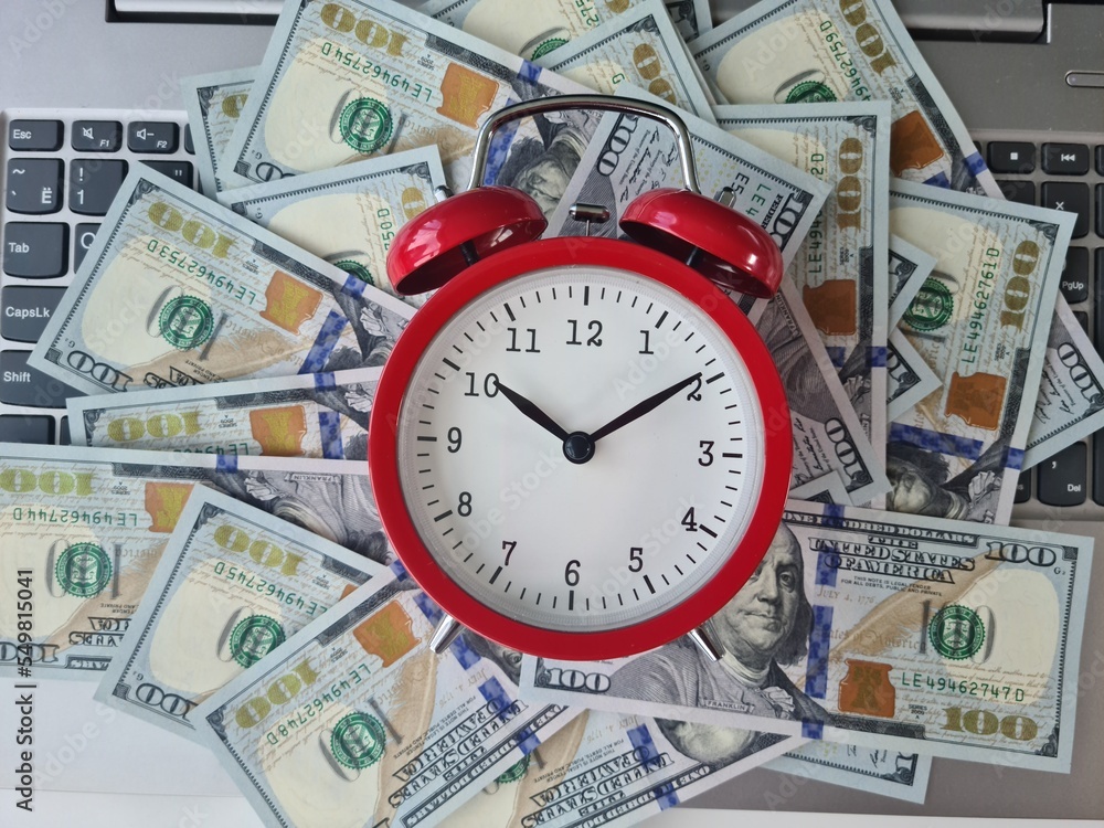 Open laptop with dollars and an alarm clock Open laptop with dollars and an alarm clock