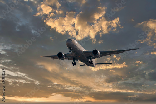 horizontal image with copy space of a plane landing full of passengers against the blue sky at a beautiful sunrise
