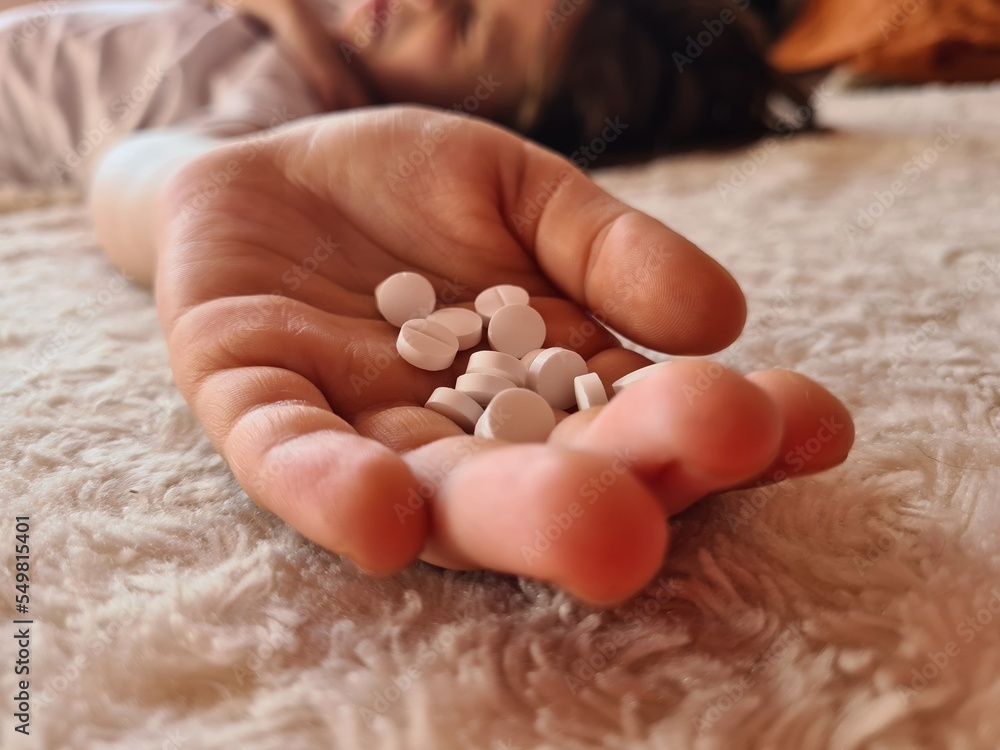Girl child took large dose of pills and lies on bed.