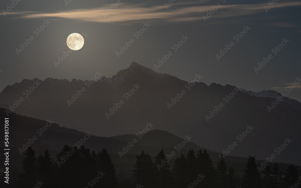 Full moon over mount Krivan peak - Slovak symbol - forest trees silhouettes in foreground, evening photo Full moon over mount Krivan peak - Slovak symbol - forest trees silhouettes in foreground, evening photo