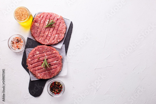 Raw fresh hamburger patties or cutlet ready to cook on white textured background.  Top view. Place for text.