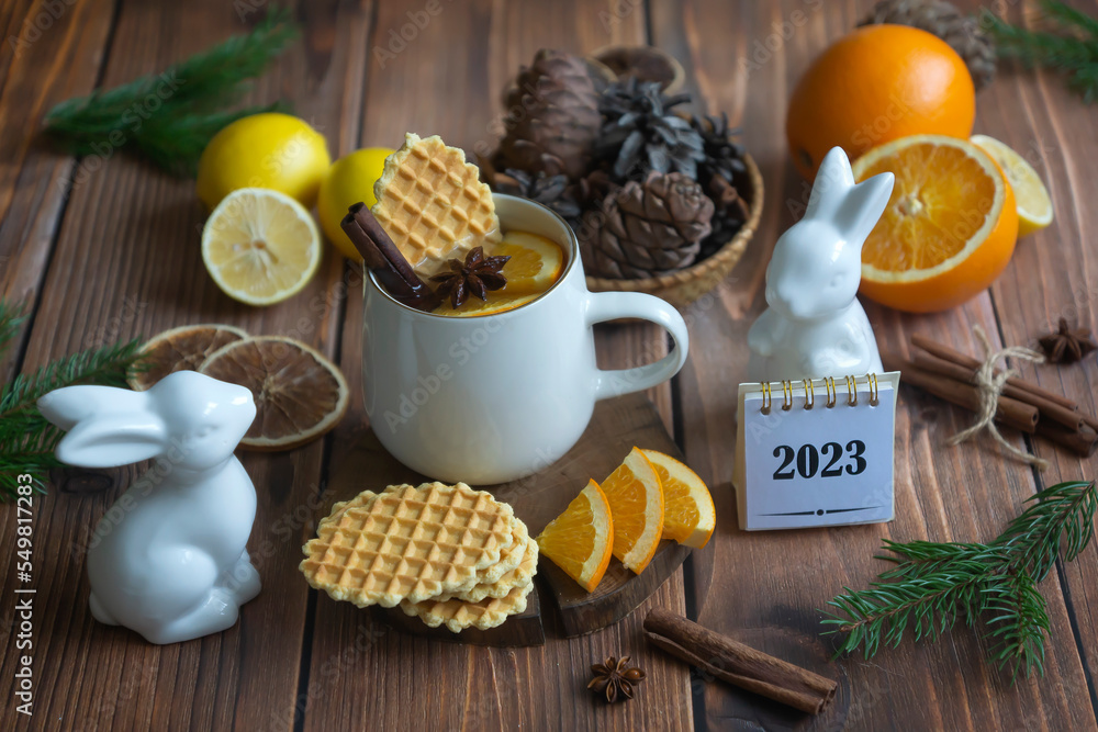 Calendar for 2023 and fragrant tea with orange and spices on a wooden table. Pie, lemons, oranges winter mood. Calendar for 2023 and fragrant tea with orange and spices on a wooden table. Pie, lemons, oranges winter mood.
