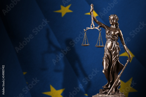 Obraz na plátně European union flag with statue of lady justice and judicial scales in dark room
