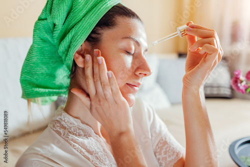 Woman applying facial hyaluronic acid serum. Skincare treatment. Product for oily skin with acne and large pores photo