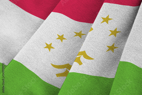 Tajikistan flag with big folds waving close up under the studio light indoors. The official symbols and colors in banner photo