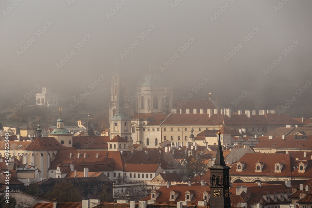 Prague panorama in foggy autumn morning,Czech Republic. View of Church of Saint Nicholas,Lesser town with historical buildings and red roofs.Amazing European cityscape.Travel architecture concept.