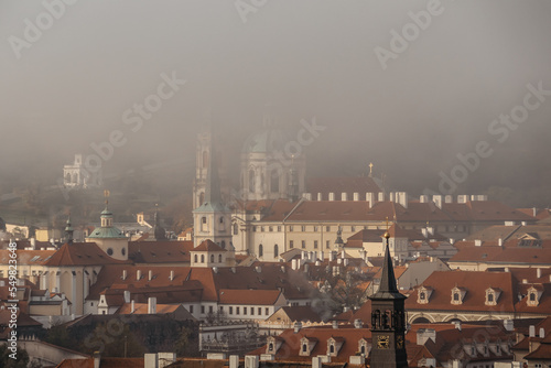 Prague panorama in foggy autumn morning,Czech Republic. View of Church of Saint Nicholas,Lesser town with historical buildings and red roofs.Amazing European cityscape.Travel architecture concept. © Eva