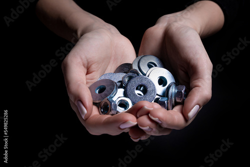 Woman's hands holding screws and dowels in palms. Isolated on black. female hands hold screws nails washers nuts on a black background
