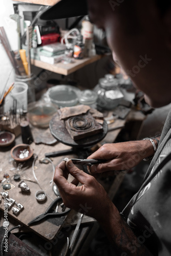 A craftsman jeweler is using the clamps to shape a metal cilinder for a bracelet