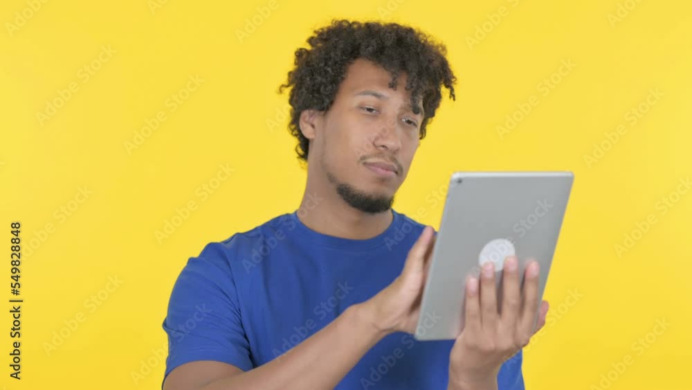 African Man using Digital Tablet on Yellow Background African Man using Digital Tablet on Yellow Background