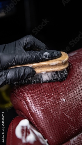 Obraz na płótnie employee of a car wash or a car detailing studio washes the leather upholstery of the car with a brush w salonie
