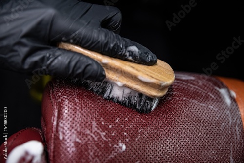 Obraz na płótnie employee of a car wash or a car detailing studio washes the leather upholstery of the car with a brush w salonie