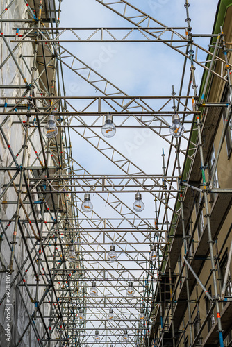 Scaffolding over a narrow street with lanps hanging underneath. photo