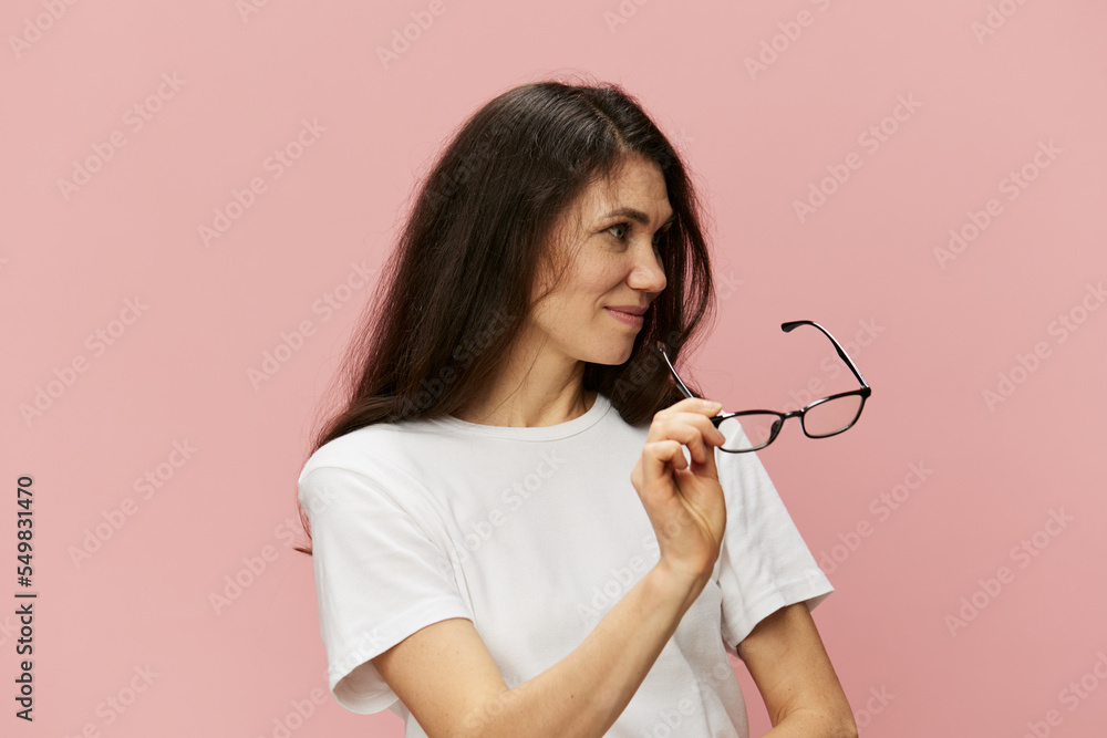 portrait of a beautiful, smart, pleasant woman with long hair, in a light T-shirt, holding glasses in her hands and looking away portrait of a beautiful, smart, pleasant woman with long hair, in a light T-shirt, holding glasses in her hands and looking away