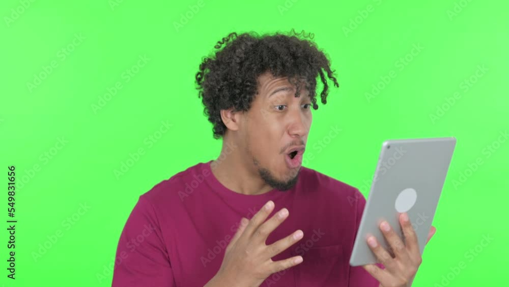 African Man Celebrating Success on Tablet on Green Background African Man Celebrating Success on Tablet on Green Background