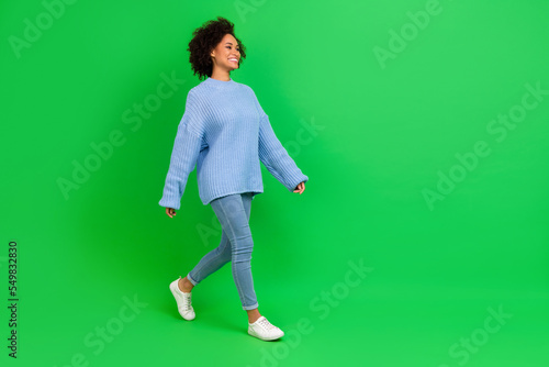 Full length photo of sweet curly lady go look promo wear pullover jeans shoes isolated on green color background © deagreez