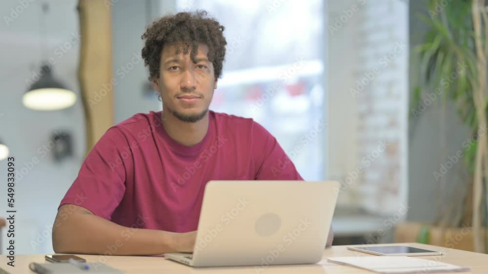 African Man Looking at Camera while using Laptop African Man Looking at Camera while using Laptop