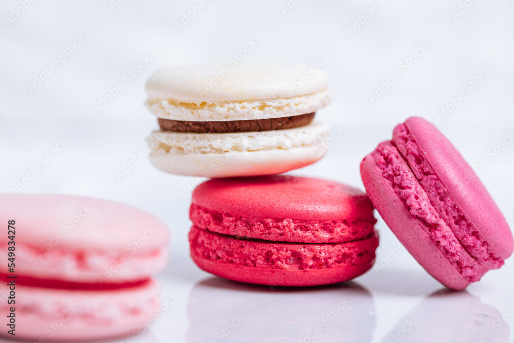Close up of Macaroons in different colours on bright white background with subtle reflection on marble tray. Popular merengue dessert with filling inside. Close up of Macaroons in different colours on bright white background with subtle reflection on marble tray. Popular merengue dessert with filling inside.