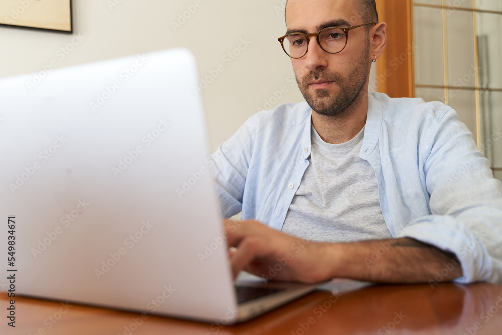 Young male with glasses using laptop Young male with glasses using laptop