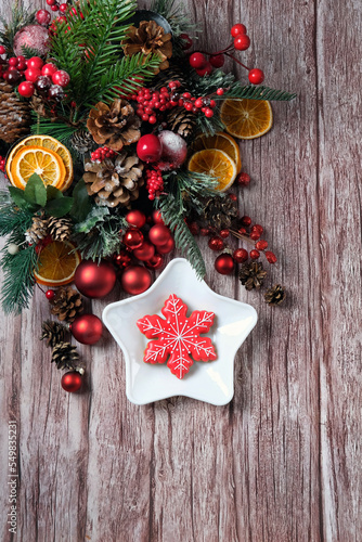 Christmas background. Gingerbread snowflake cookie on plate, dried citrus slices, cones, fir tree branches, decor on old wooden rustic table. festive winter season. top view. copy space