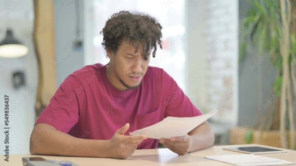 African Man Upset while Reading Documents in Office African Man Upset while Reading Documents in Office
