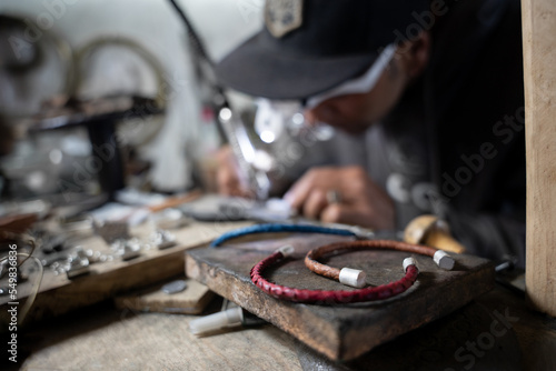 A craftsman jeweler is making handmade bracelets